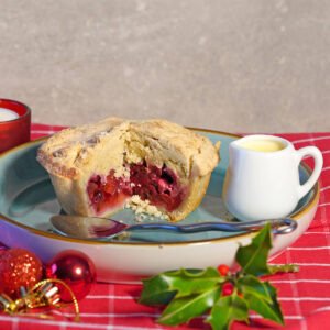 Plum and blackberry crumble cut with a small jug of cream